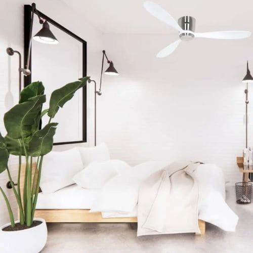 Ventilateur de plafond blanc au-dessus d'une chambre lumineuse et épurée: lit, plantes et lampe murale, ambiance calme. Comment choisir un ventilateur de plafond pour chambre.