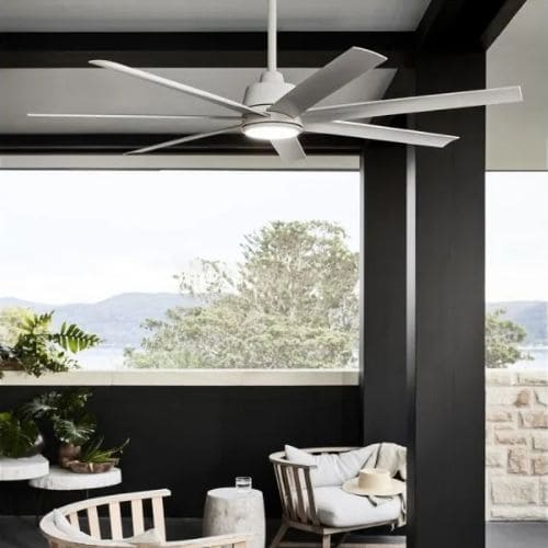Ventilateur de plafond moderne en extérieur couvert, tournant lentement sous un auvent avec vue sur paysage et mobilier chic. pourquoi mon ventilateur de plafond fait du bruit intégré naturellement.