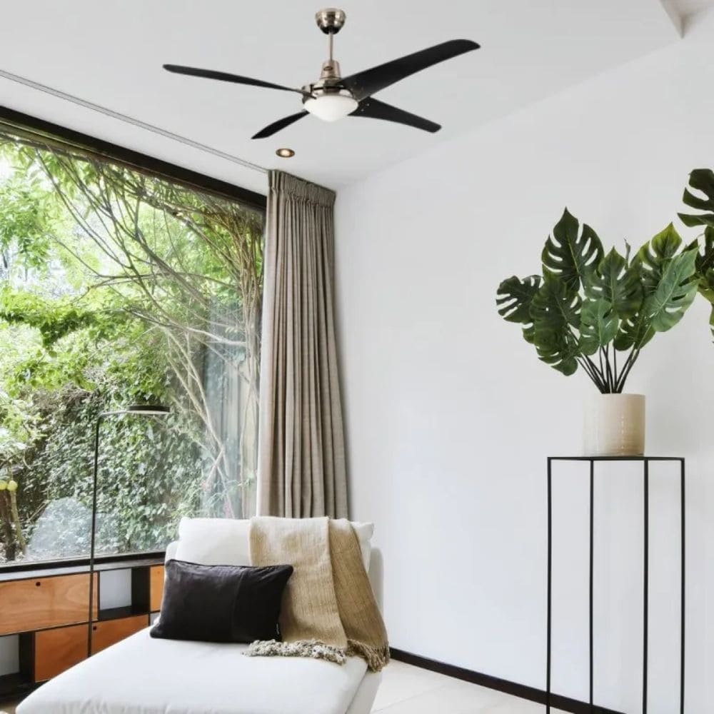 Ventilateur plafonnier noir à 3 pales dans un salon lumineux, canapé blanc avec coussins, grande baie vitrée et plantes décoratives. pourquoi ventilateur fait du bruit integrate.
