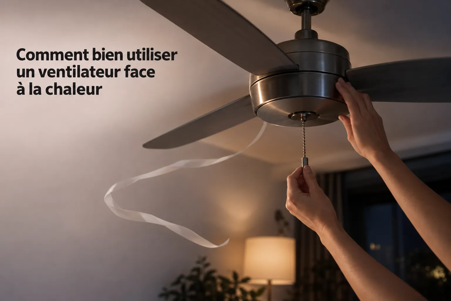 Comment bien utiliser un ventilateur face à la chaleur : personne ajuste la chaîne du ventilateur au plafond dans une pièce éclairée.