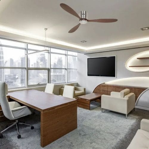 Ventilateur de plafond moderne à trois pales dans un salon-bureau lumineux, avec canapé et poste de travail, adapté à un espace contemporain.