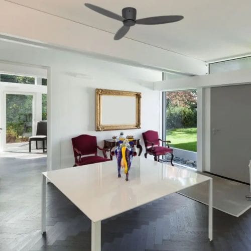 Ventilateur au plafond dans une salle à manger lumineuse avec table blanche et chaises rouges.